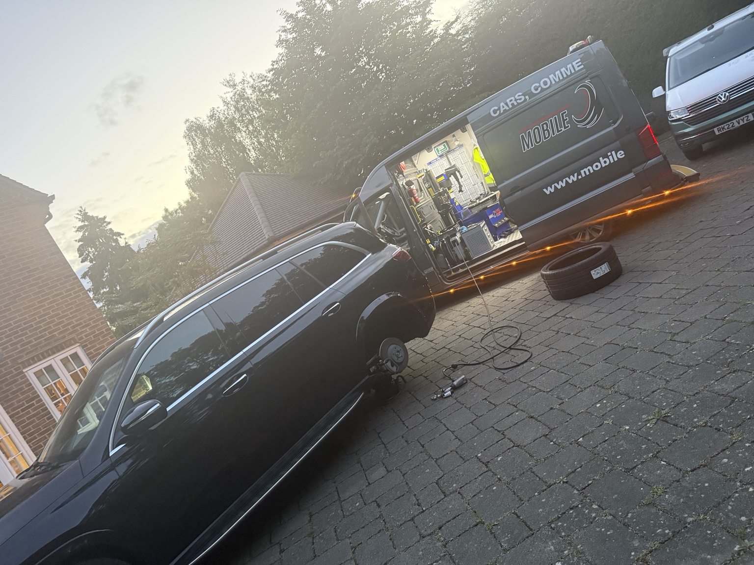 Car tyre fitting on a driveway beside the equipped van