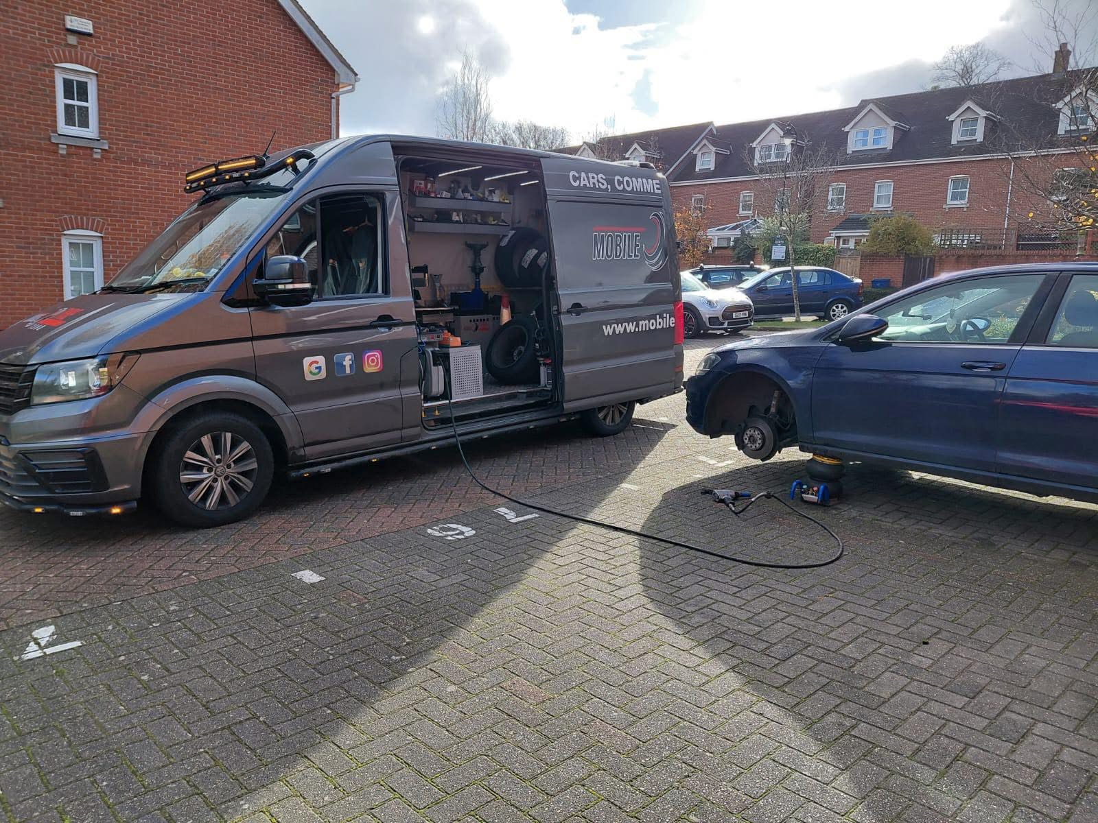 Equipped Mobile Tyre Tech van beside a blue car during tyre fitting in a residential car park