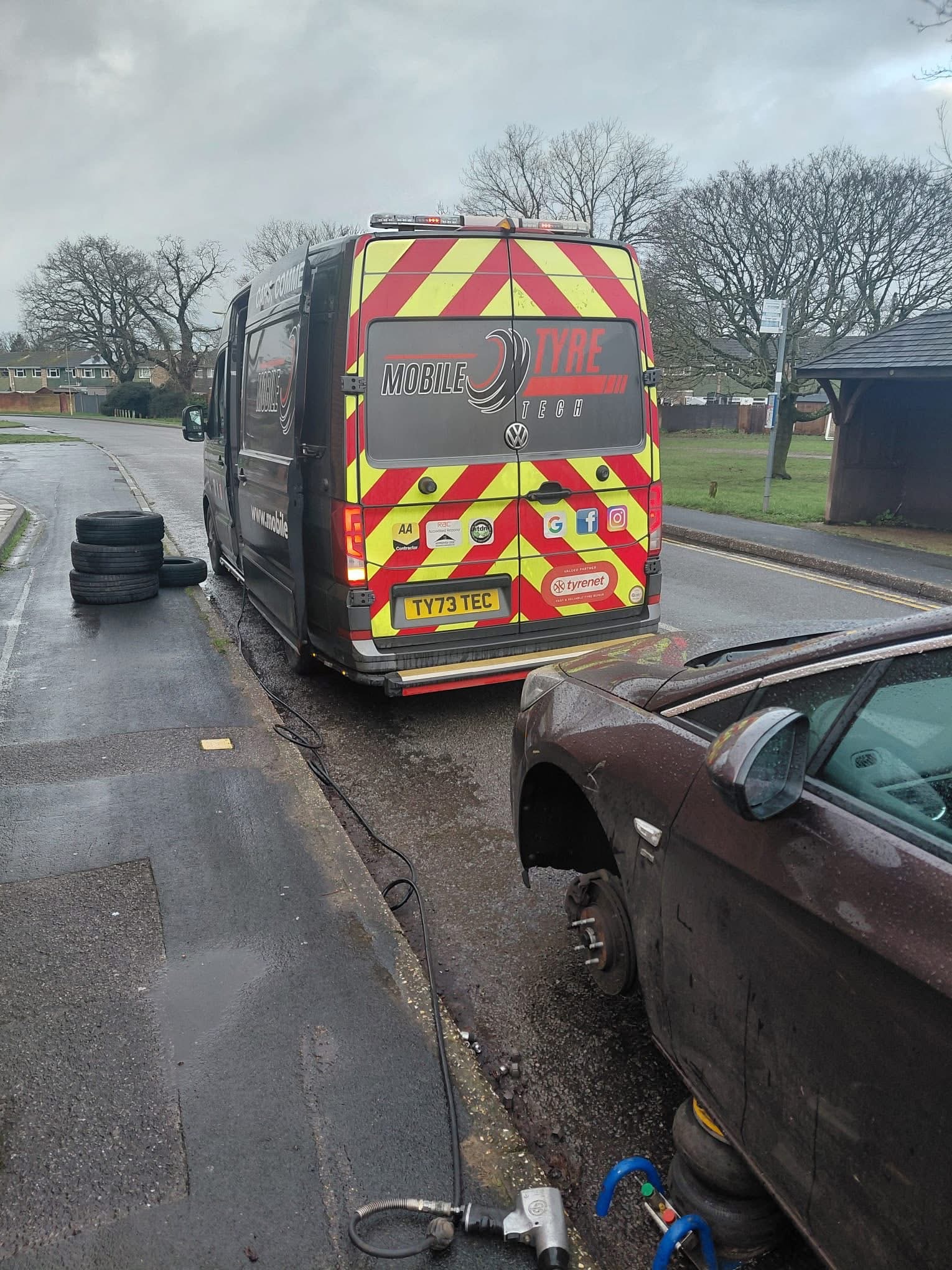 Mobile Tyre Tech van with rear safety markings beside a car with its front wheel removed